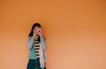 Woman in Blue Jacket Holding Pink Fujifilm Instax Camera