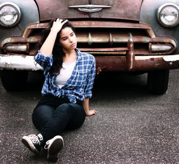 Woman in Blue Sports Shirt Sitting Infront of Vintage Brown Car