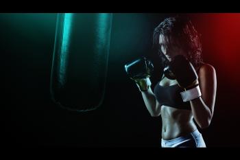 Woman in Boxing Gloves With Sports Bra Posing Boxing Style in Front of Punching Bag