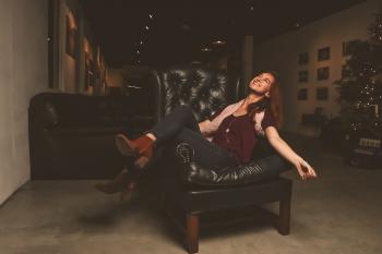 Woman in Maroon Scoop-neck Shirt Sitting on Black Leather Sofa Chair
