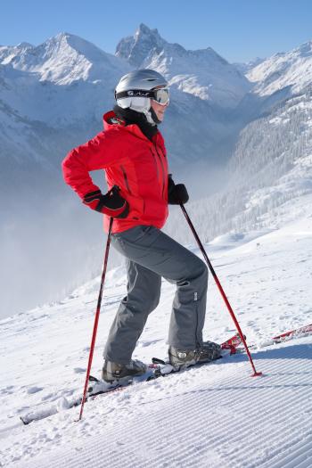 Woman in Red Jacket Wearing Helmet and Holding Snow Ski Stick