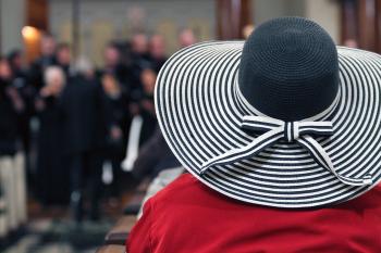 Woman in Red Shirt and Black and White Stripes Sunhat Surrounded by People
