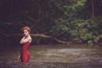 Woman in Red String Spaghetti Strap Dress on Body of Water Near Forest
