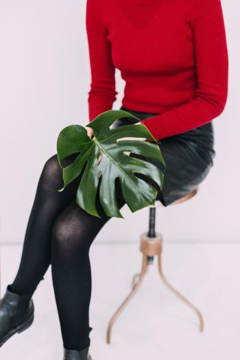 Woman in Red Sweater and Black Pants Holding Green Leaf