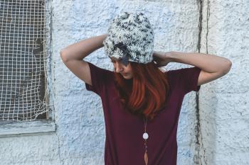 Woman in White and Black Knit Cap Posing Near White Wall