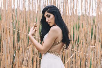 Woman in White Backless Dress in Front of Bamboo Sticks