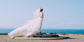 Woman in White Bridal Gown Standing in Brown Round Concrete Surface Under Blue Sky during Day Time