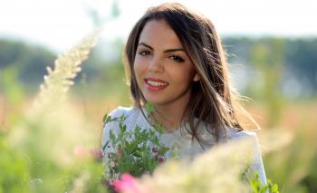 Woman in White Crew Neck Shirt Smiling and Surround With Flowers and Plants during Daytime