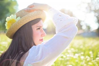 Woman in White Long Sleeve Shirt Wearing a Straw Hat during Daytime at Flower Field