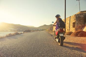Woman Riding Motor Scooter Travelling on Asphalt Road during Sunrise