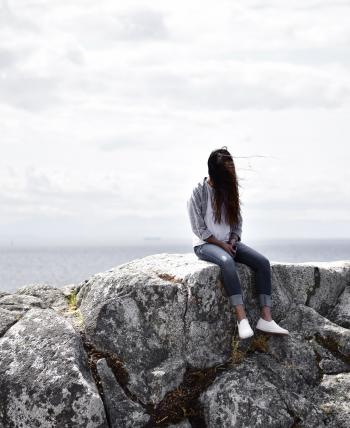 Woman Sits on Gray Rock