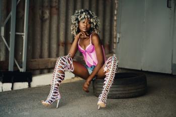 Woman Sitting on Vehicle Tire Wearing Pink Lingerie and White Gladiator Pumps