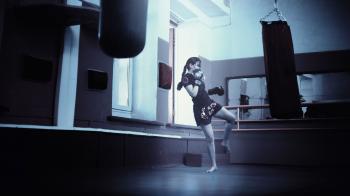 Woman Training in a Gym Kicking a Training Bag