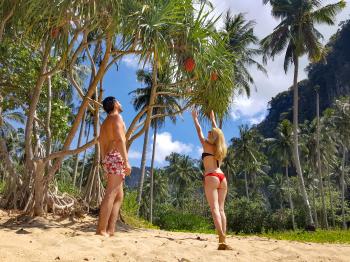 Woman Wearing Black Bikini Top and Red Bottom Beside Man Wearing White and Red Floral Shorts