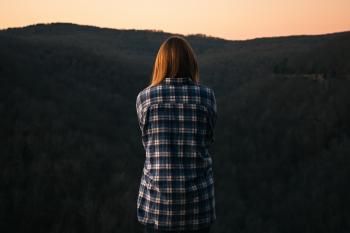 Woman Wearing Blue and White Plaid Dress Shirt in Front of Green Mountain