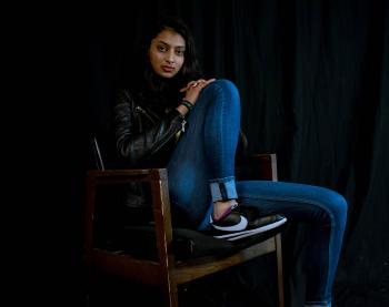 Woman Wearing Blue Jeans Sitting on Brown Wooden Armchair