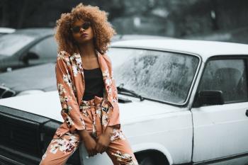 Woman Wearing Brown Floral Print Coat and Pants Sitting on Car