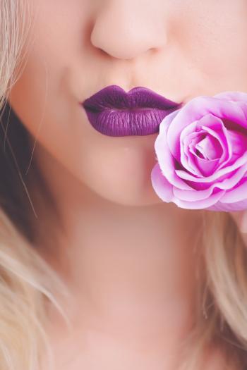 Woman Wearing Purple Lipstick With Pink Rose on Her Cheeks