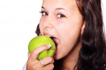 Woman Wearing Silver Diamond Ring Biting Green Apple
