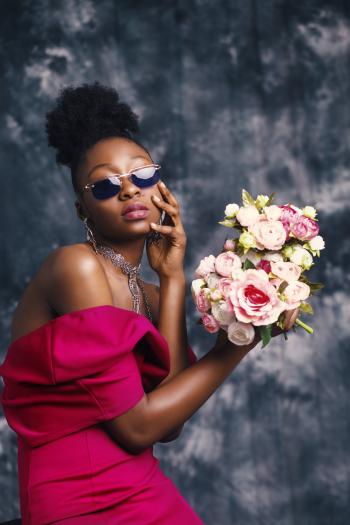 Woman Wearing Sunglasses and Posing for Pic With Flowers