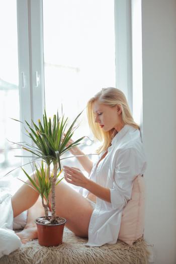 Woman Wearing White Long-sleeved Shirt Sitting Beside Green Plant