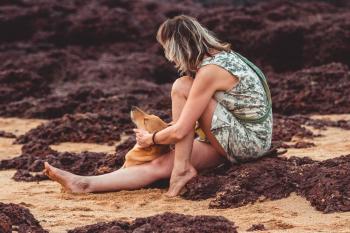 Woman With Green Floral Sleeveless Mini Dress Sitting on Brown Sand Close-up Photography