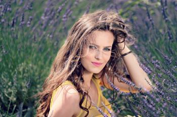 Women's Yellow Tank Top Holding Her Brown Curly Hair While Sitting on a Purple Flower