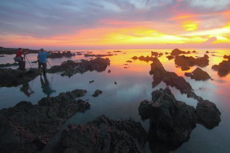 2 People Standing on Rock Formation Reflected on Water during Sunset