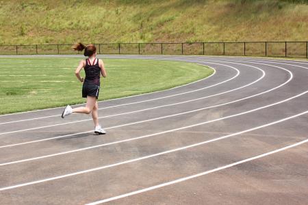 A cute young girl running on a track
