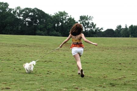 A cute young girl running with her dog