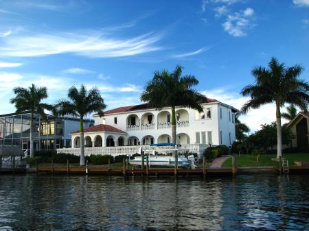 A fancy house along the water with palms