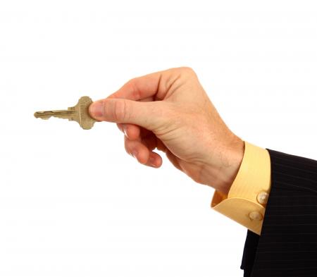 A hand in a business suit holding a key