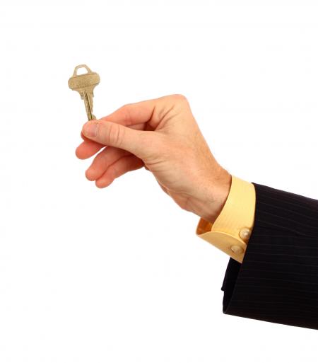 A hand in a business suit holding a key