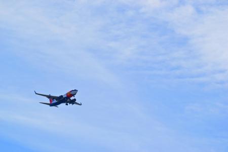 A red and blue passenger airplane is flying in the sky
