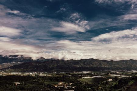 Aerial Photography of Grass Field Near Mountain Under White Cloudy Sky