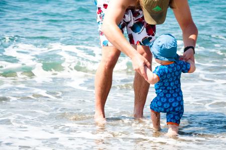 baby boy with father playing in the ocea