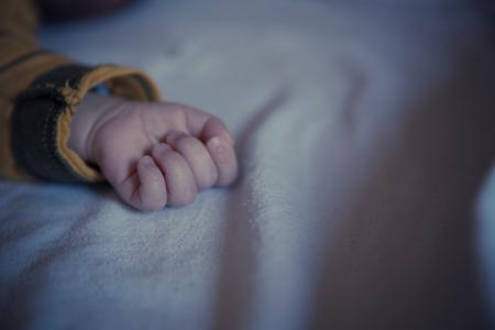 Baby in Yellow and Black Long Sleeved Shirt Lying on White Textile