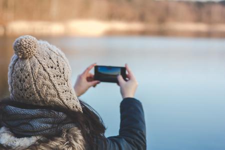 Back view of a woman taking photo with a smartphone