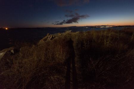 Bay at night with long shadow on rocky outcrop