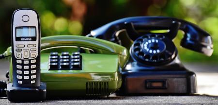 Black and Green Rotary Telephones Beside Cordless Home Telephone