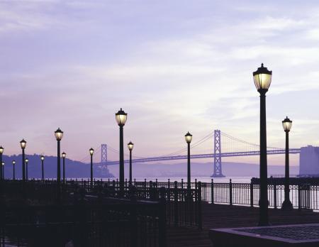 Black and White Light Post on Road Under Cloudy Sky during Sunset