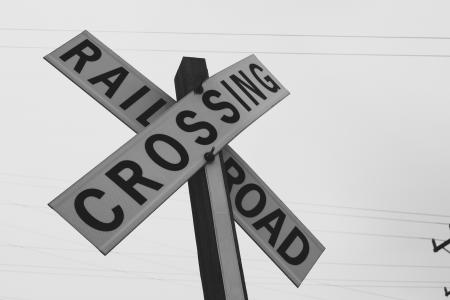 Black and white photo of a road sign near the railway