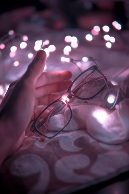 Black Frame Eyeglasses and White String Lights in White Textile