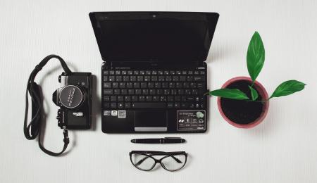 Black Laptop Black Camera and Plant Near Each Other on White Tile