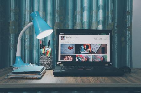 Black Laptop Computer Near Blue Study Lamp on Brown Wooden Table