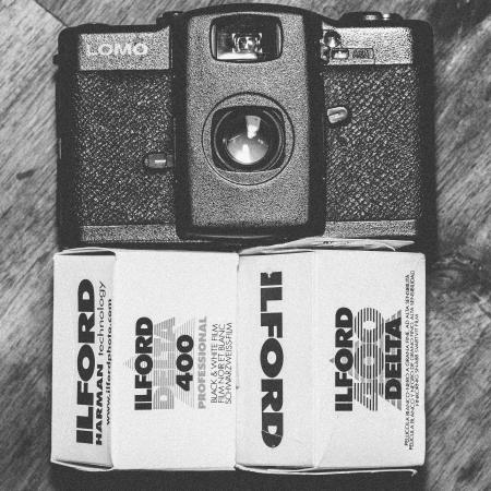 Black Lomo Compact Camera Beside Ilford Delta 400 Black & White Film Box