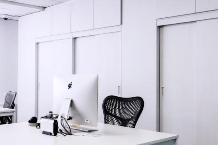 Black Mesh Office Rolling Chair Beside White Wooden Desk With White Imac