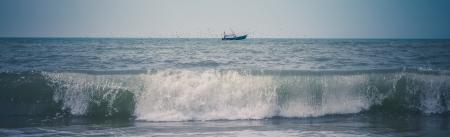 Black Ship on Green Sea Under White and Blue Sky at Daytime