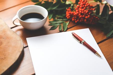 Blank paper with pen and coffee cup on wood table