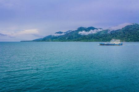 Blue and White Yacht on Teal Sea Near Green Mountain